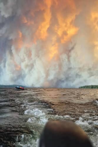 Collins First Nation residents flee wildfires on a boat in Collins, Ontario, on 13 July 2026.