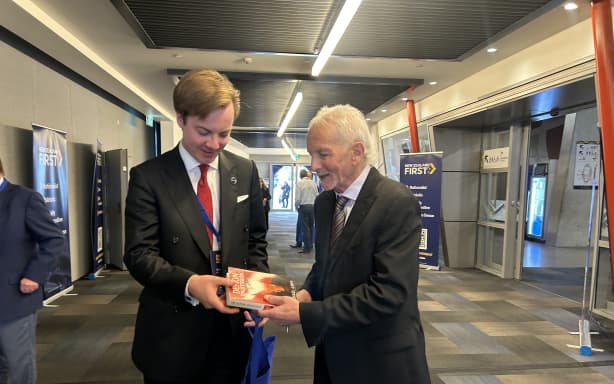 Michael Laws signs a book for a supporter at the NZ First party conference in Auckland, July 2026.
