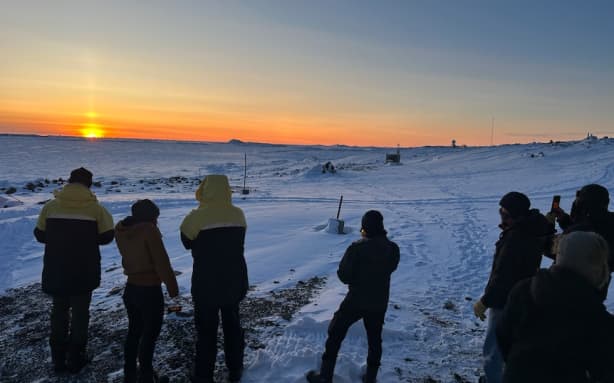 A group of expeditioners gathers at Davis Station to experience 24 minutes of sun above the horizon.