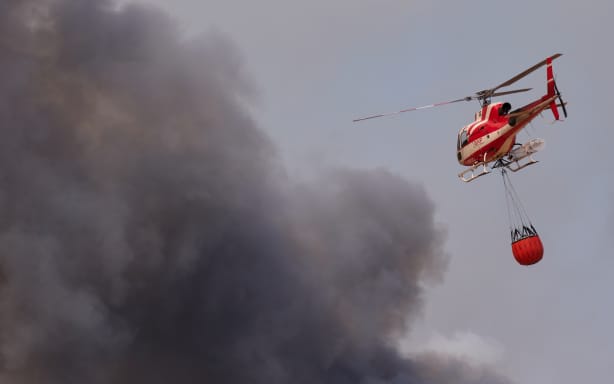 FONTAINEBLEAU, FRANCE - JULY 13: Firefighting helicopters with a suspended water bucket collect water from a temporary reservoir established by firefighters and local farmers to combat the wildfire, after a wildfire broke out in the Fontainebleau Forest on July 13, 2026 in Fontainebleau, France. The fire began yesterday in the former royal hunting preserve, which is about 40 miles outside Paris. (Photo by Pierre Crom/Getty Images)