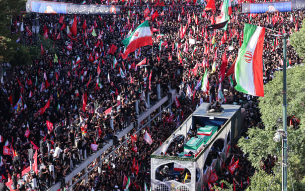 Crowds of mourners surround the convoy carrying the coffins of Iran's slain supreme leader Ali Khamenei and members of his family during a funeral procession, before he is buried at the Shrine of Imam Reza, Iran's most revered place of worship, in Mashhad on July 9, 2026. Braving sweltering heat and calling for revenge, Iranians loyal to the Islamic republic massed on July 9 for the burial of slain supreme leader Ali Khamenei in his hometown of Mashhad. (Photo by ATTA KENARE / AFP) /