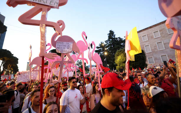 Protesters hold cutouts of flamingos as they demonstrate in front of the Albanian Prime Minister's Office against the construction of a luxury resort near a protected natural area on Albania's southern coast, in Tirana, on July 4, 2026. Since late May 2026 protesters have gathered every evening to oppose the construction of a luxury hotel linked to US President's son-in-law, Jared Kushner. The demonstrators argue that the estimated $4 billion project, led by Kushner and his wife Ivanka, will harm the environment, with plans for luxury hotels in the protected area of Vjosa-Narta on the southern coast. (Photo by Adnan Beci / AFP)