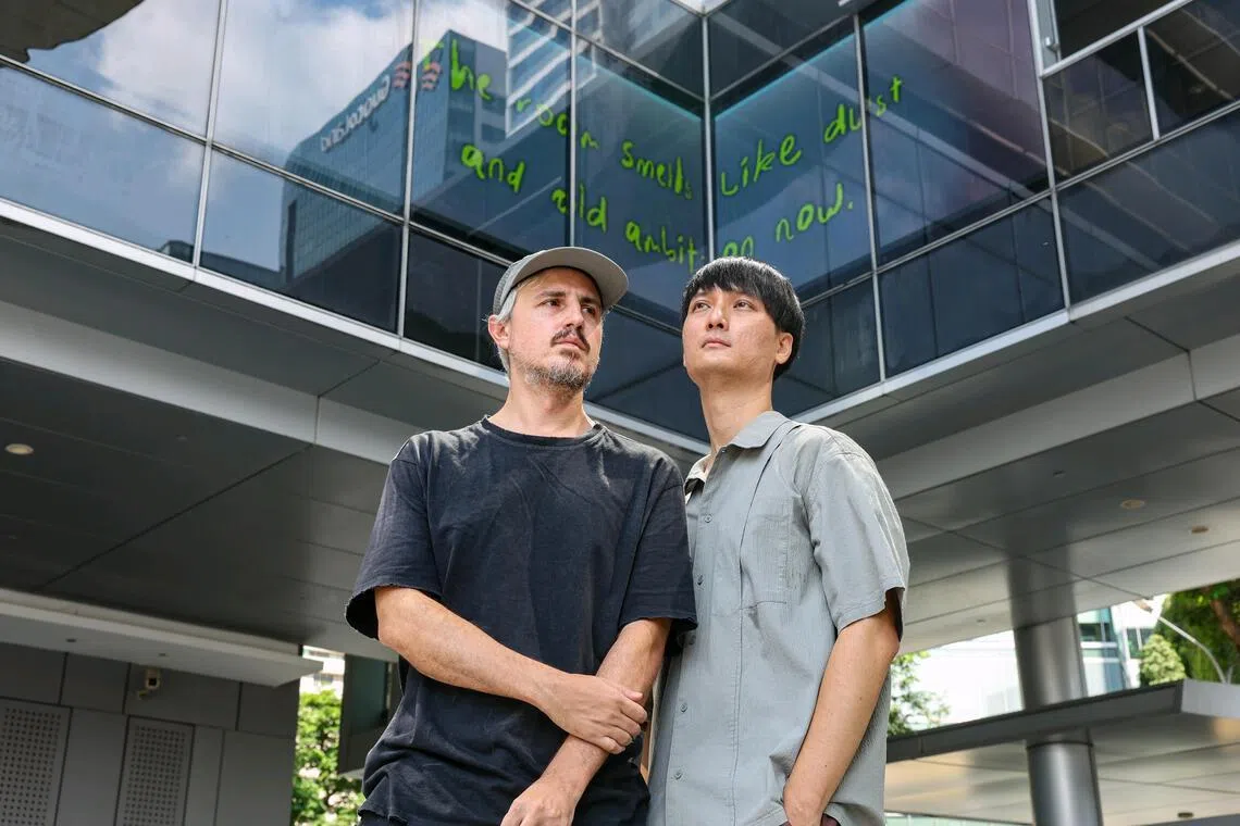 (From left) Artists Federico Ruberto and Teo Yue Han with their artwork thusspoke.baby, a real-time generative video and text transparent LED display, at OUE Link on July 1, 2026. The artwork is part of the Singapore Art Museum's first public art trail in Singapore's Central Business District. ST PHOTO: BRIAN TEO