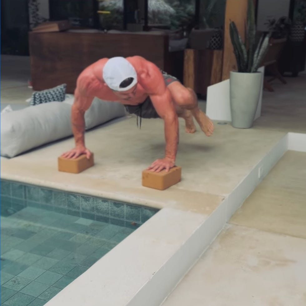 man balancing in a handstand on bricks by a pool. man balancing in a handstand on bricks by a pool.