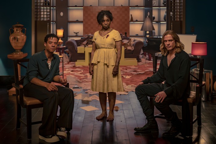 571865,TITLE:The Vampire Lestat: Interview with the Vampire s3 Louis and Lestat sit in a 1980s-era living room, with the ghost of Claudia stood between them