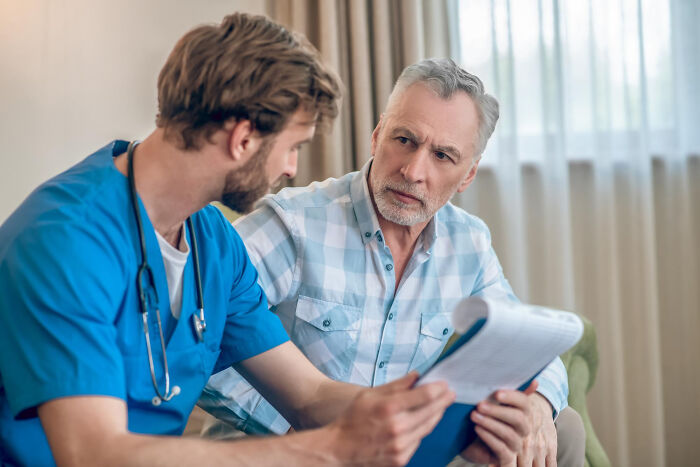 Male medical professional discussing a chart with an concerned older man, highlighting uncomfortable truths about the medical industry.