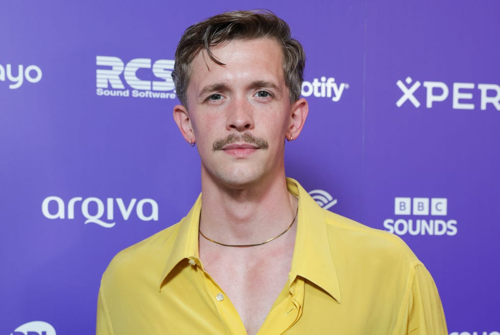 Stephen Libby stephen libby wearing a yellow shirt and standing against a purple branded backdrop