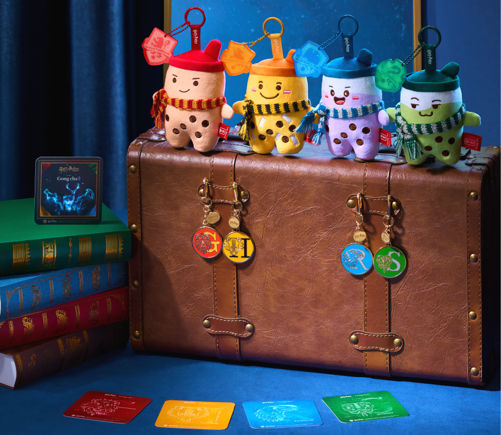 Colorful plush keychains themed around Harry Potter on a suitcase with books and collectible cards. Colorful plush keychains themed around Harry Potter on a suitcase with books and collectible cards.
