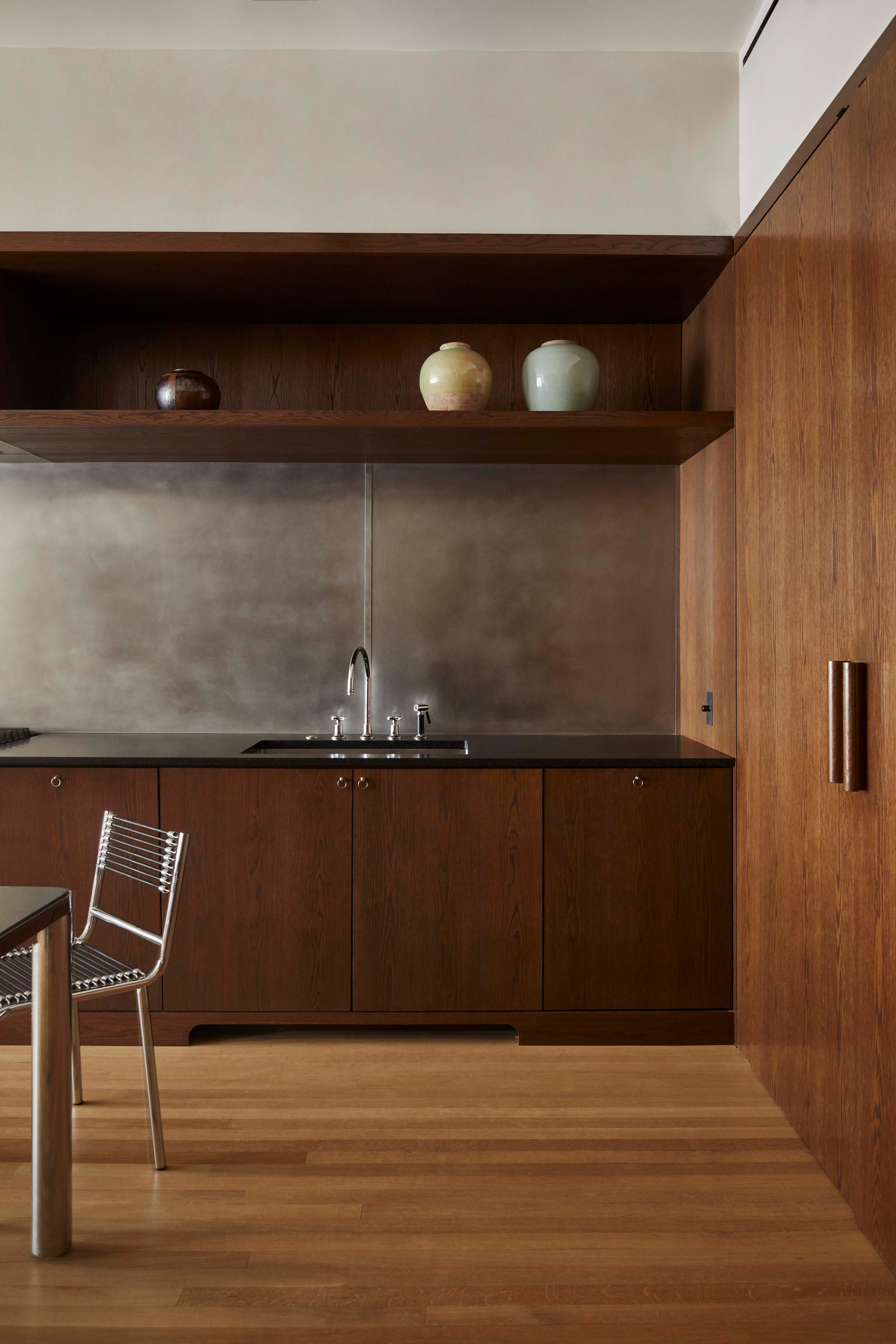 Modern kitchen featuring dark wood cabinetry, a sleek countertop, and decorative vases on a shelf.