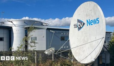 STV News headquarters featuring a large satellite dish, modern architecture, and a clear blue sky with scattered clouds.