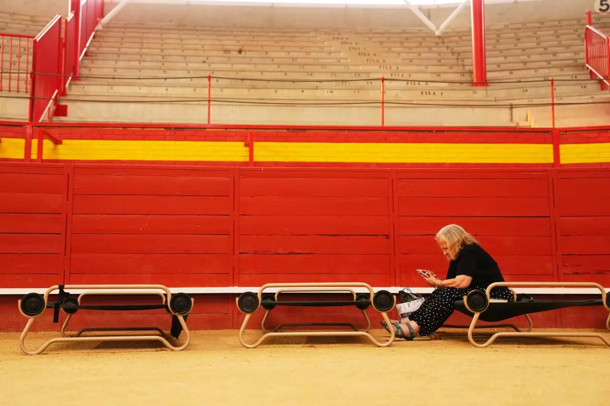 A resident sits at a bullring serving as a temporary shelter after being evacuated from their homes because of the threat of a wildfire in Valdemorillo, Madrid province, Spain, Saturday, July 25, 2026. (AP Photo/Manu Fernandez)