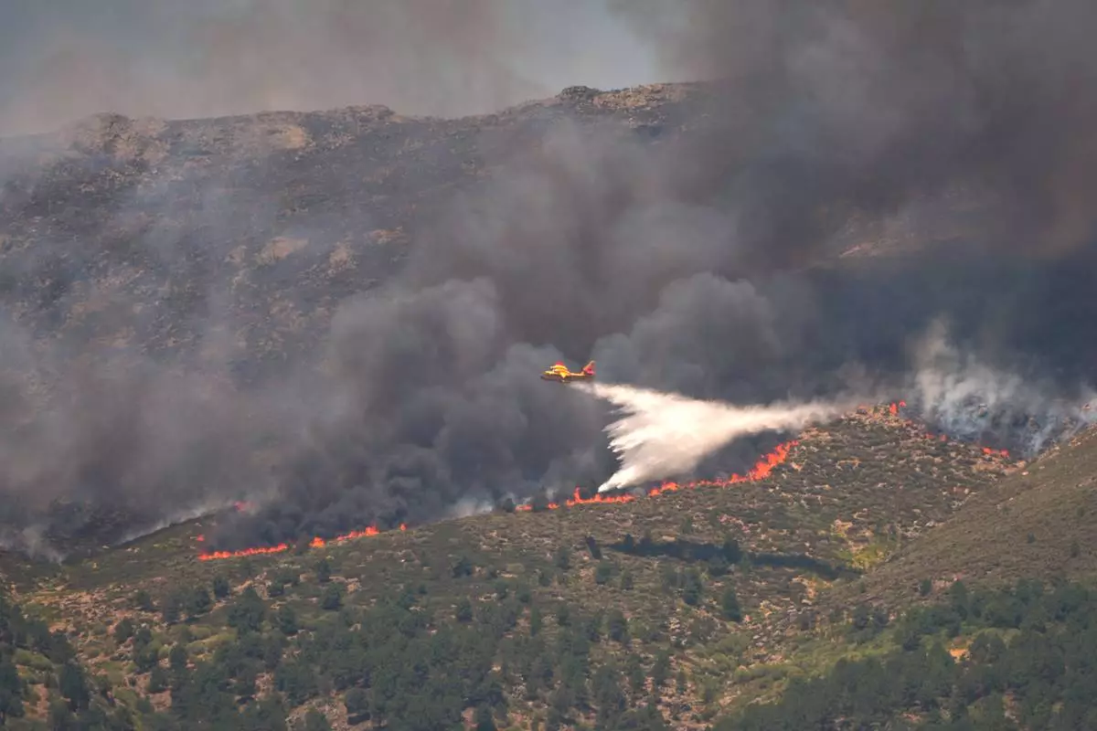 A seaplane drops water onto the fire as a wildfire advances near La Adrada, Ávila province, Spain, Friday, July 24, 2026. (AP Photo/Manu Fernandez)
