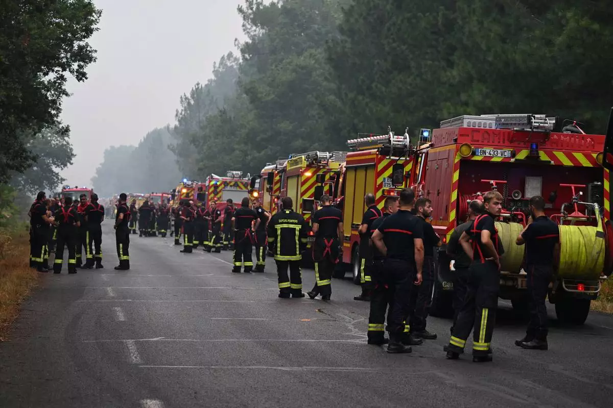 Firefighters wait on a road near Lacanau, southwestern France, Saturday, July 25, 2026. (AP Photo/Emma Da Silva)