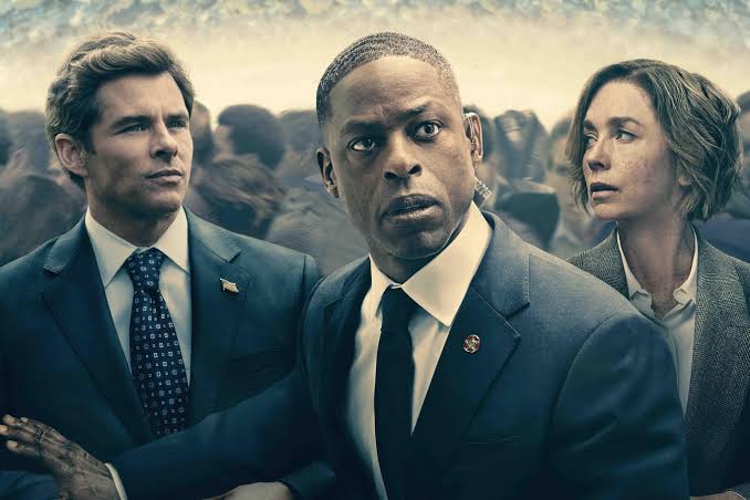 A tense group of three people in suits&mdash;two men and a woman&mdash;look urgently in different directions amidst a crowded background.