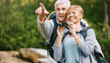 Elderly, couple hiking and bird watching with adventure outdoor, hike together and fitness for active lifestyle. Nature, trekking and senior man pointing and woman with binocular, freedom and travel.
