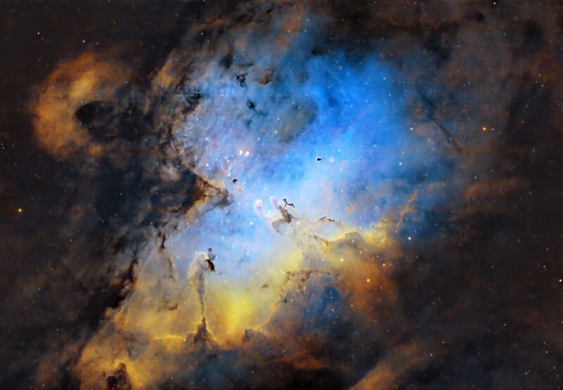 An eagle-shaped, expansive swirl of yellow and blue nebulosity with numerous background stars.