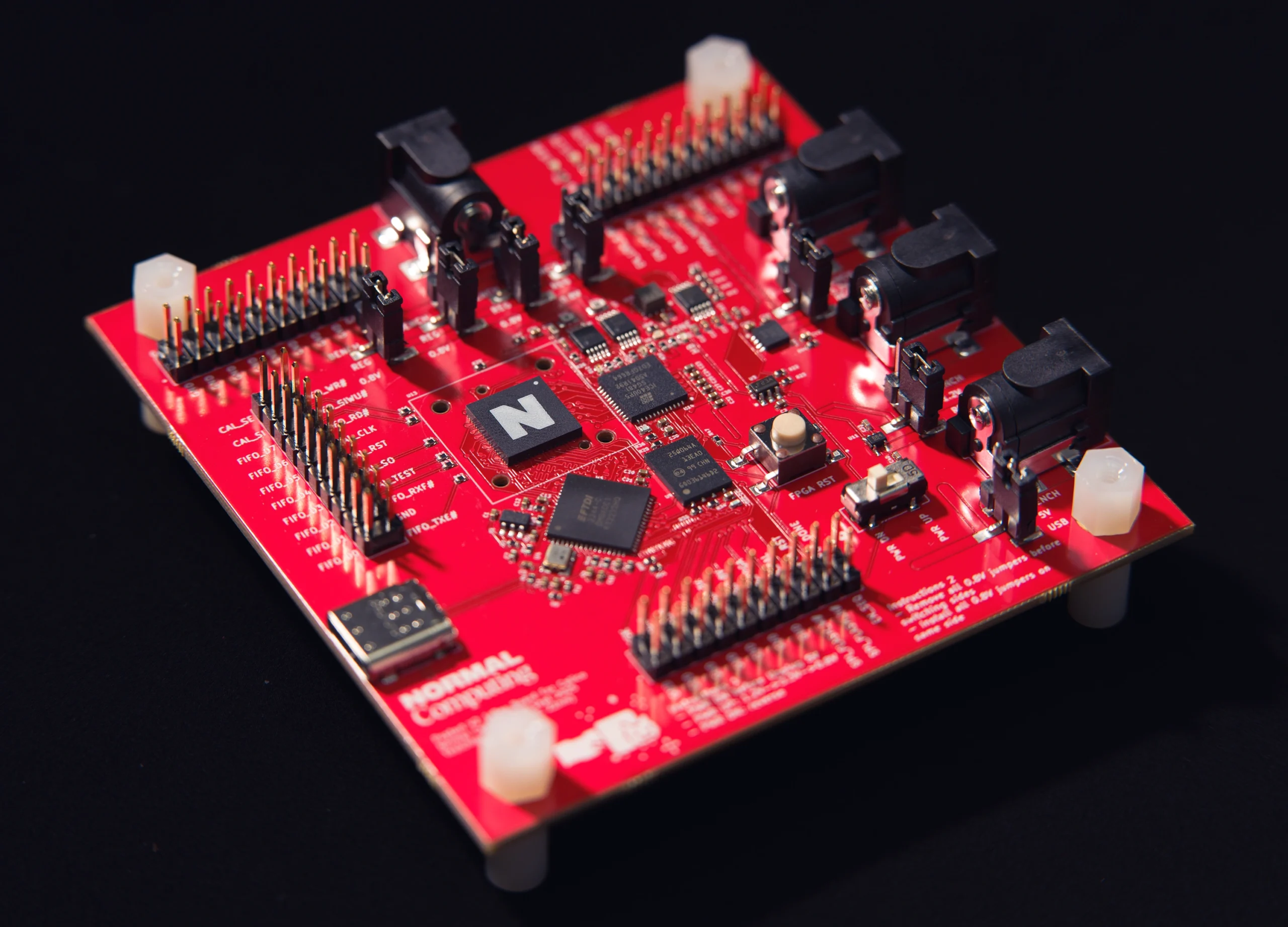 A bright red circuit board marked with the logo for Normal Computing