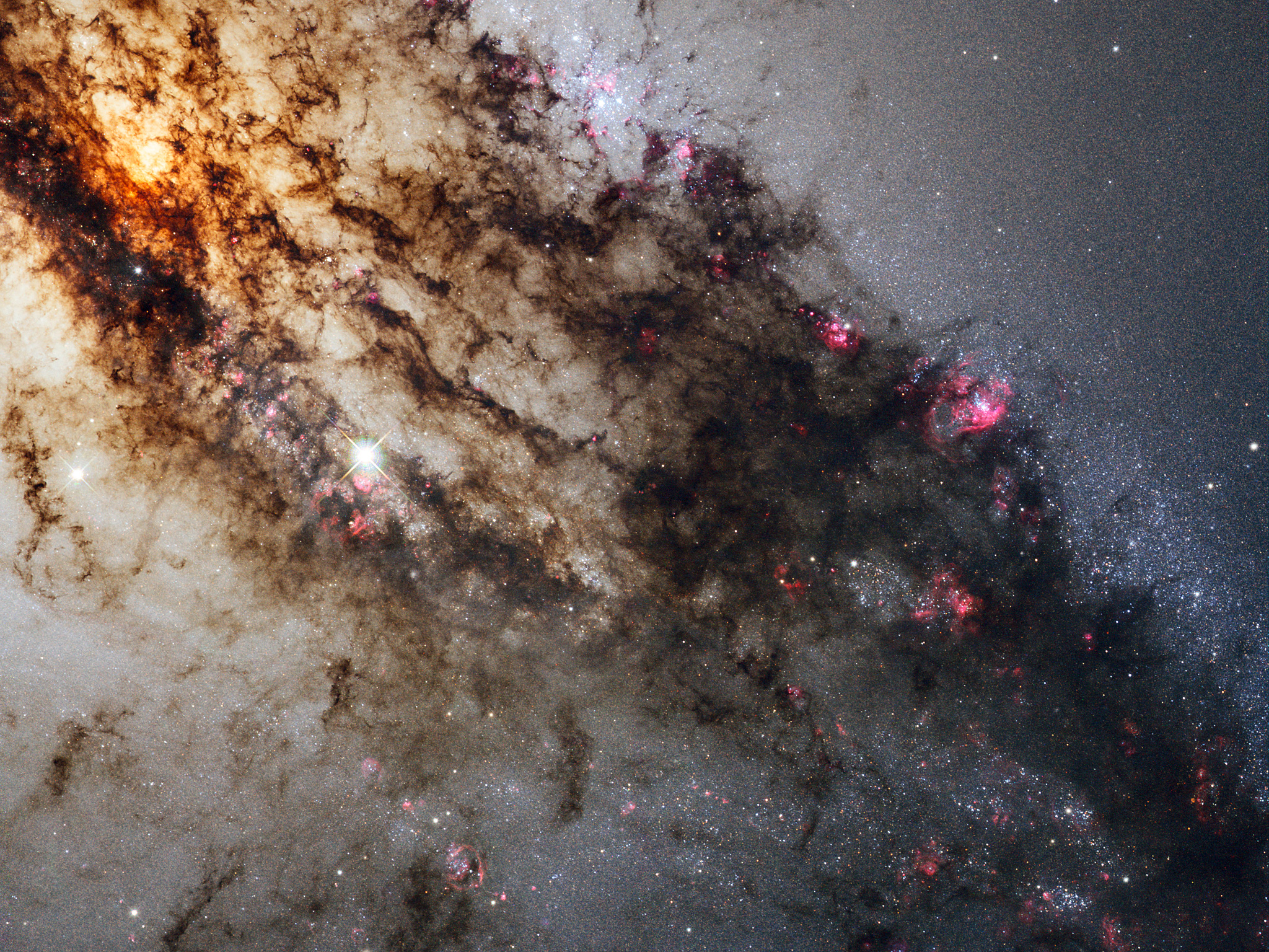 Centaurus A, also known as NGC 5128, is well known for its dramatic dusty lanes of dark material. A swirling cloud of dark gas is seen in deep space.