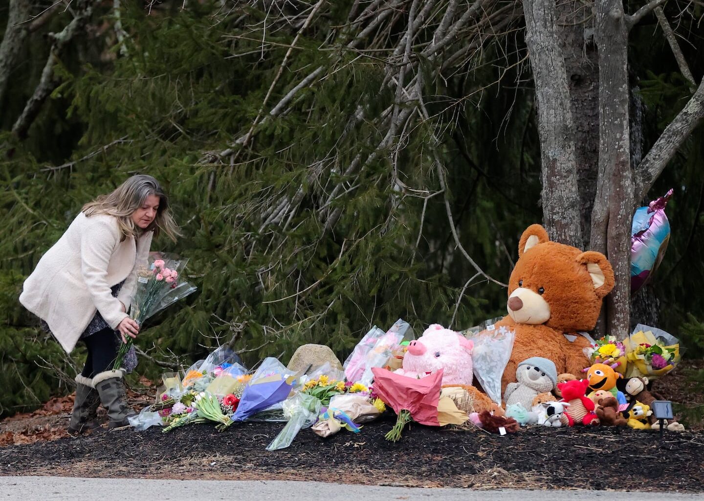 An unidentified woman left flowers at a makeshift shrine in front of the home of Lindsay Clancy, who is charged with murdering her three children, in January 2023.