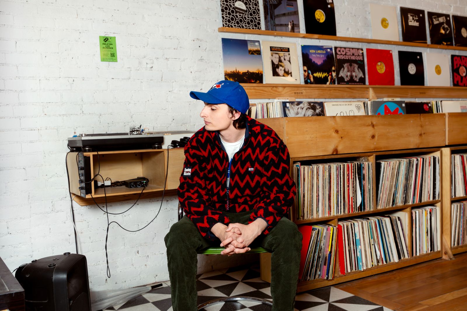 Image may contain Finn Wolfhard Baseball Cap Cap Clothing Hat Person Sitting Pants Teen Face Head and Photography