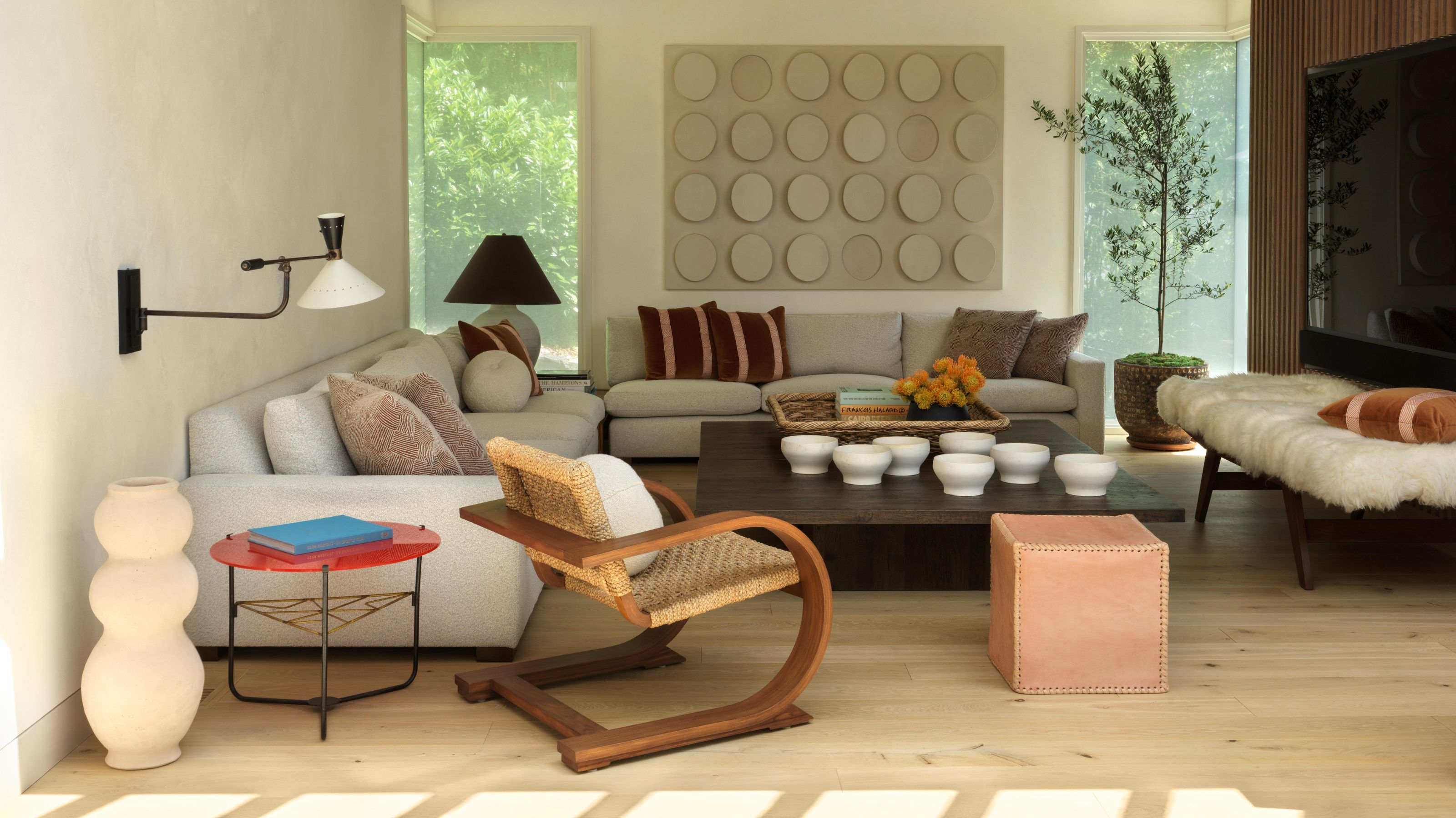 an open plan living room with two neutral sofas, an antique wooden chair, leather stool, fur topped bench and large coffee table