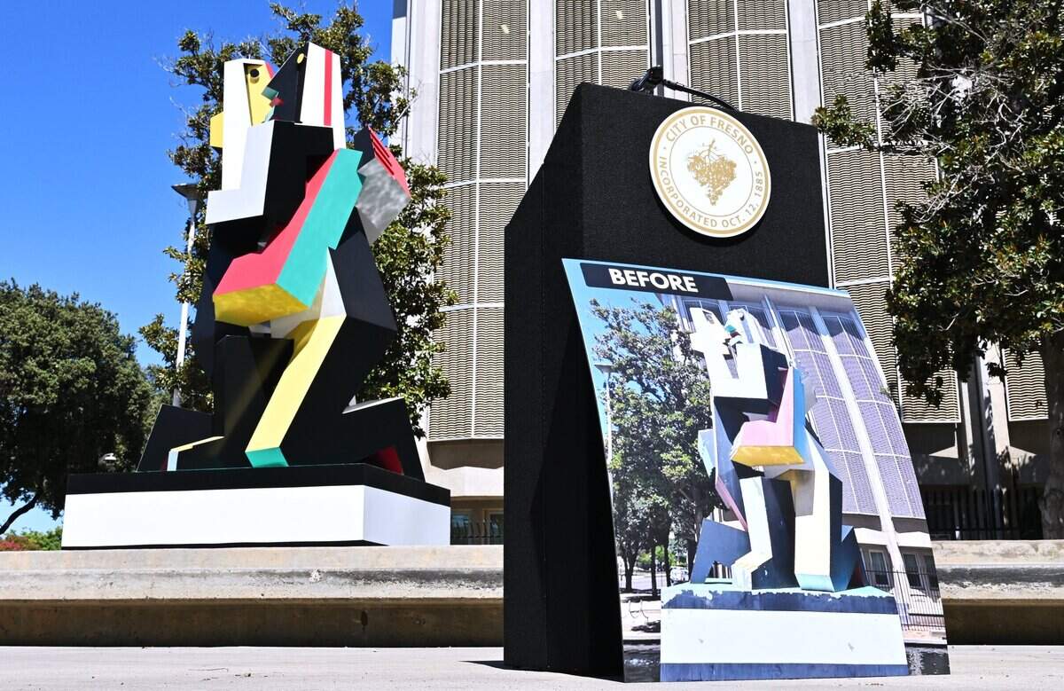 A photograph showing the sculpture Dos Amantes in faded paint is seen to the right as the newly restored statue Dos Amantes, left, located on the Mariposa Mall is revealed to media in a brief ceremony Tuesday, July 28, 2026 in downtown Fresno.