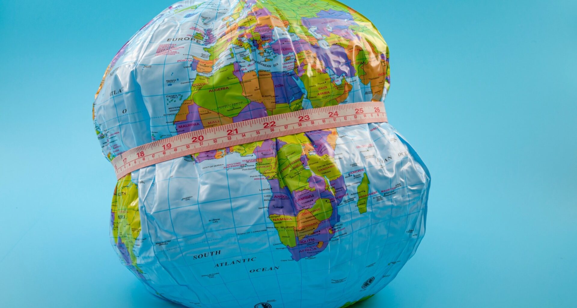 globe with measuring tape wrapped around it. Isolated on blue background.