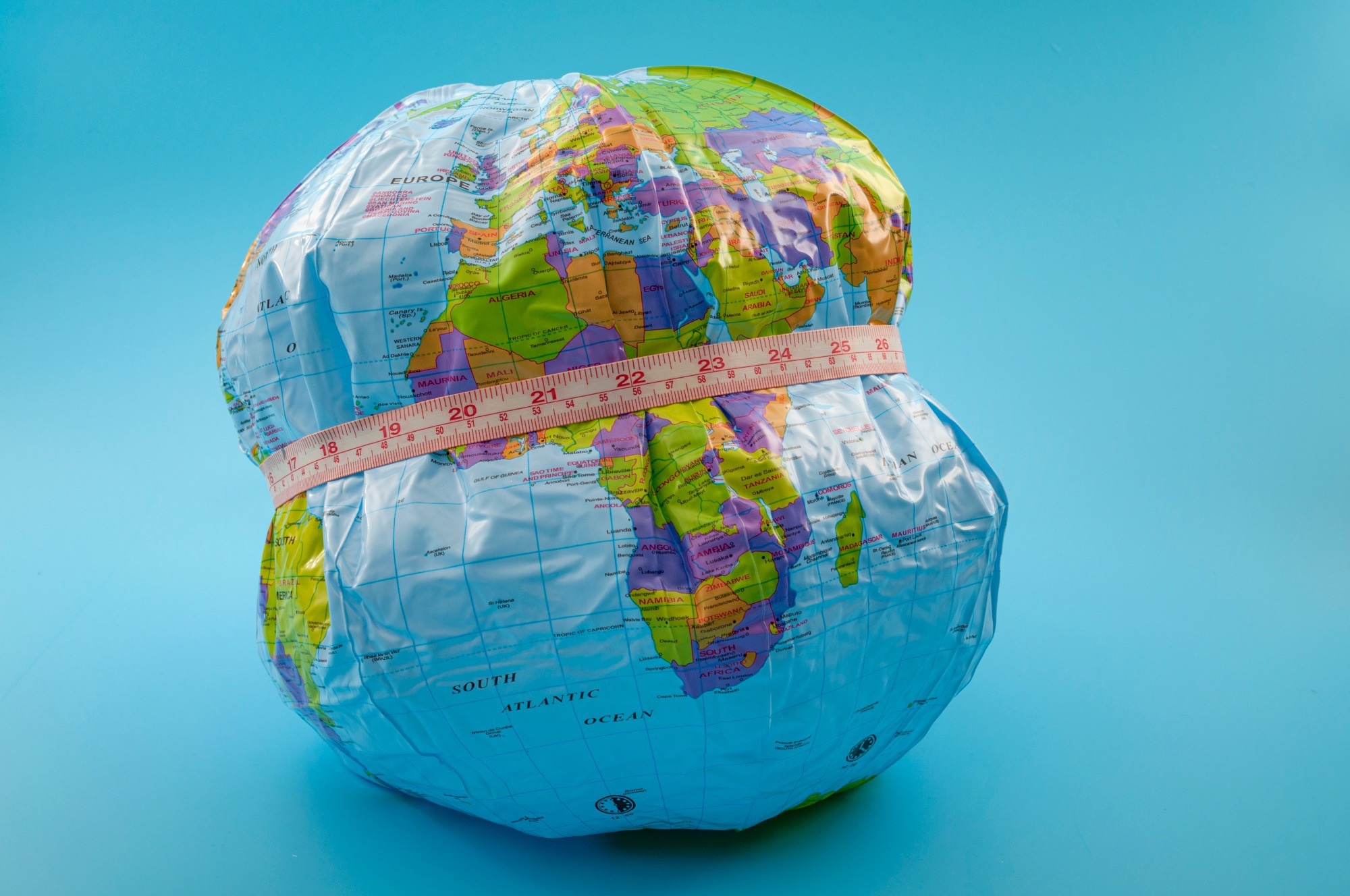 globe with measuring tape wrapped around it. Isolated on blue background.