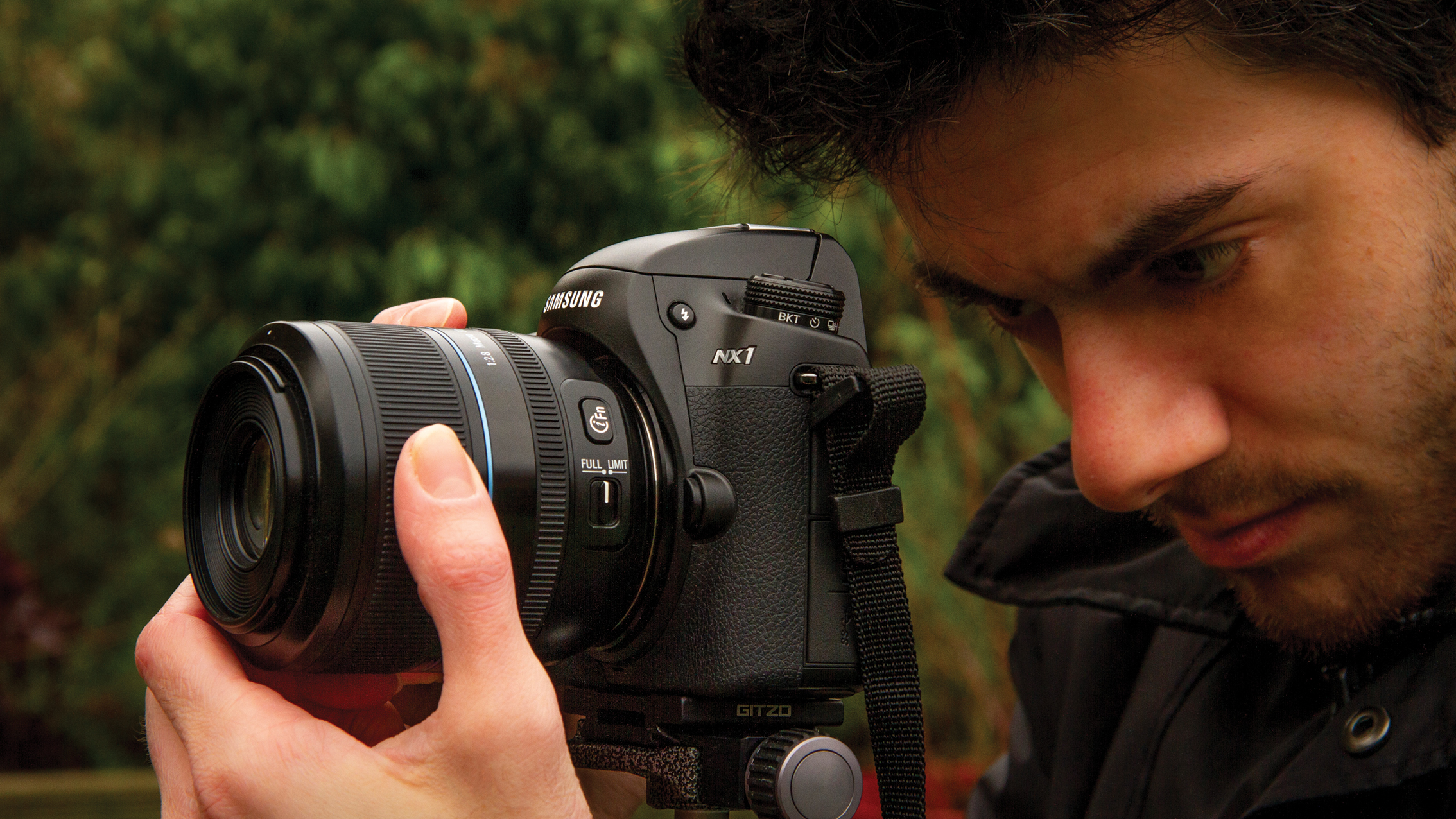 Close-up of a man intently adjusting a Samsung NX1 camera with a large lens outdoors