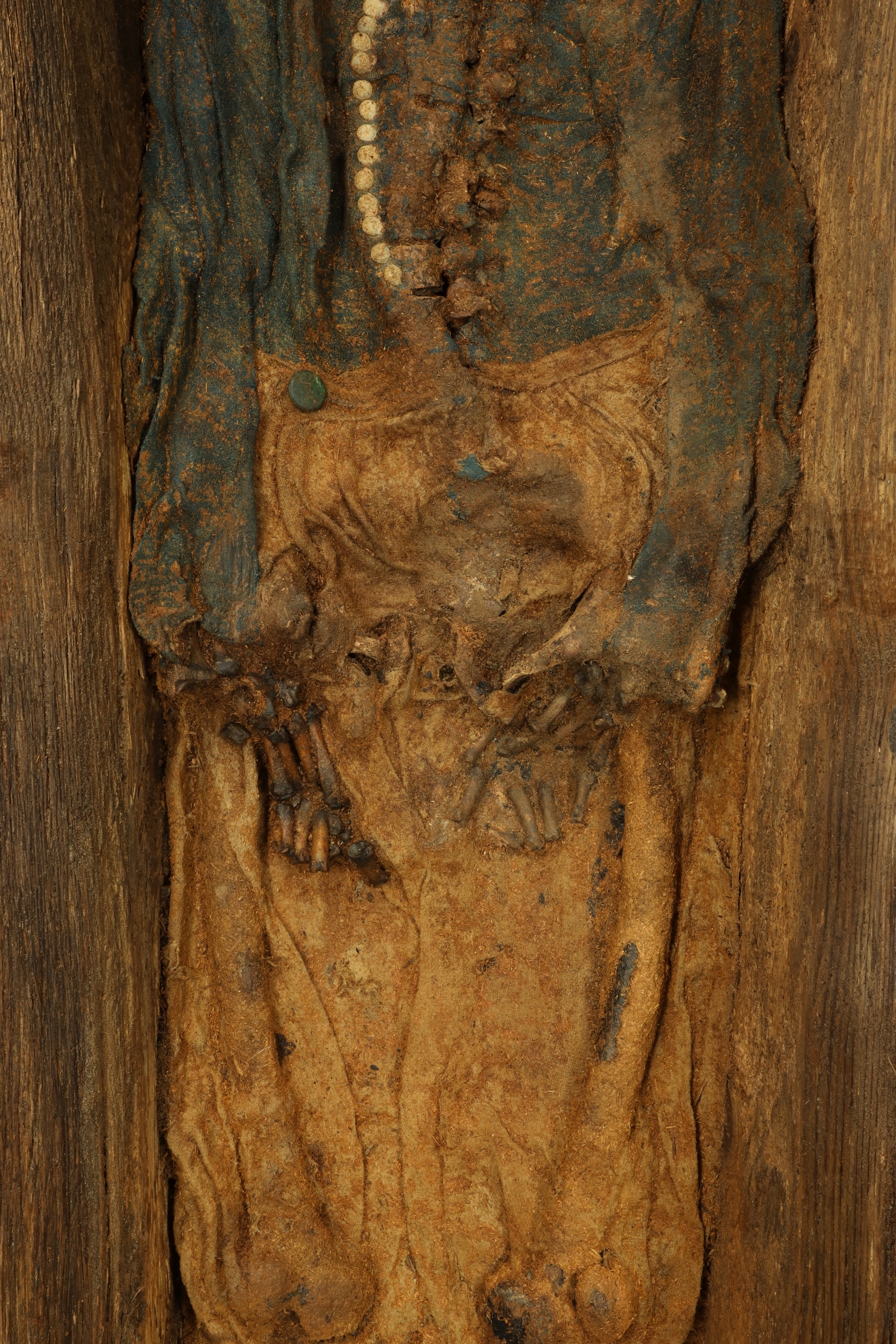A skeleton in woolen clothes lying in a wood coffin