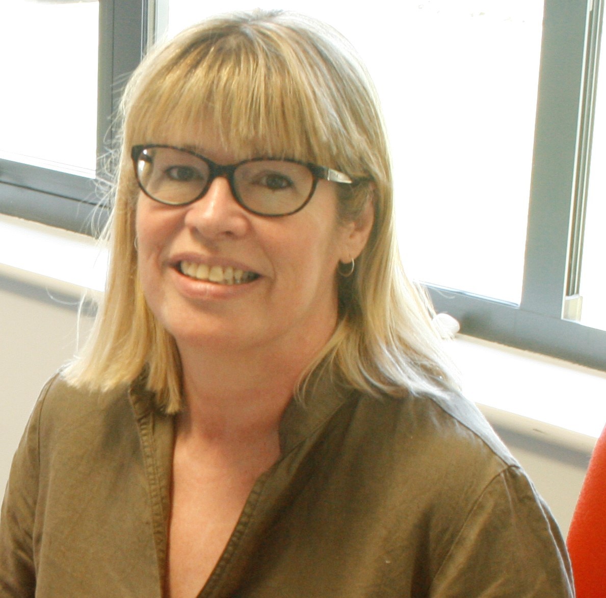 woman facing the camera and smiling with a window behind her