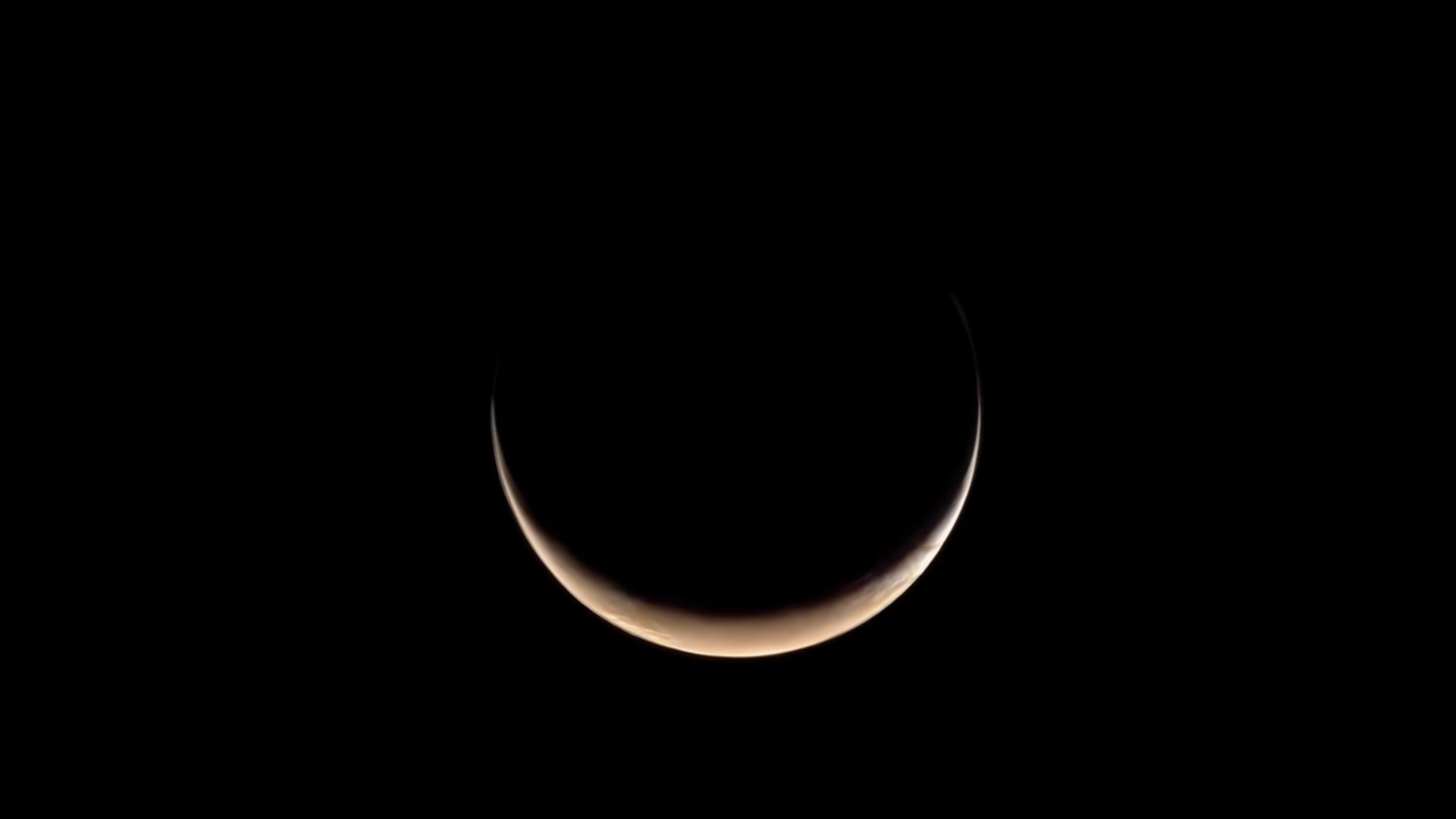 A crescent that's slightly reddish over a pitch black background.