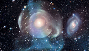 A starfield surrounds a complex background galaxy.
The galaxy center is surrounded by numerous shells, some
circular and concentric, but others colorful and 
filamentary. 
Please see the explanation for more detailed information.