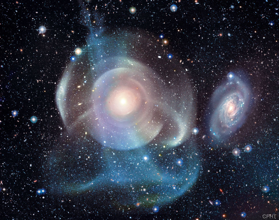 A starfield surrounds a complex background galaxy.
The galaxy center is surrounded by numerous shells, some
circular and concentric, but others colorful and 
filamentary. 
Please see the explanation for more detailed information.