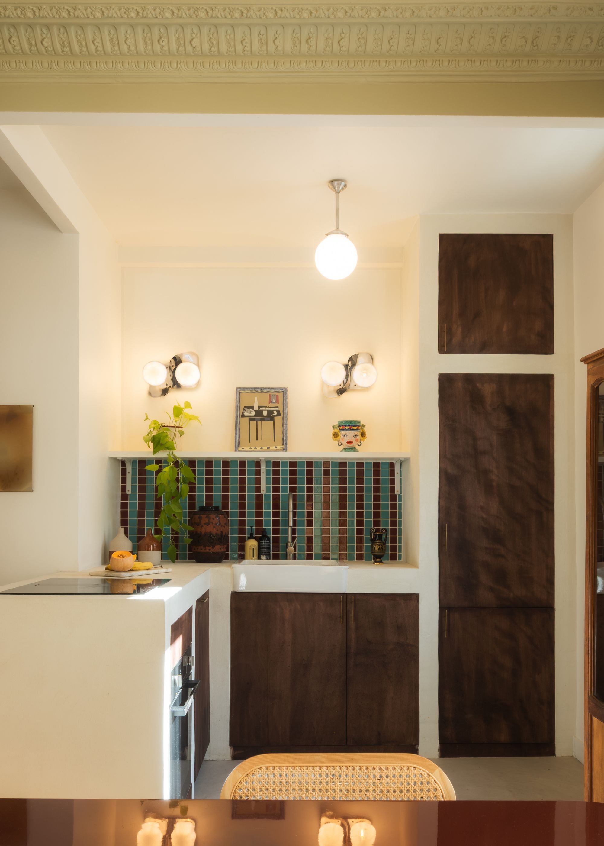 A kitchen with lime-painted ceiling, a small kitchen with multicolored backsplash tiles, and a connected dining
