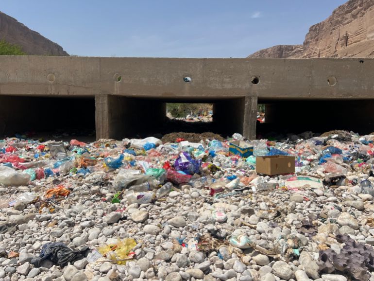 Plastic waste and household rubbish accumulate beneath a bridge in Wadi Daw’an, where residents say seasonal floods wash the debris into irrigation channels serving nearby farms. [Saeed Al-BatatiAl Jazeera]