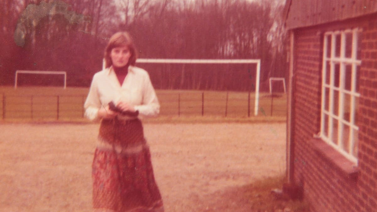 An old photograph of Princess Diana standing outdoors in a dress.
