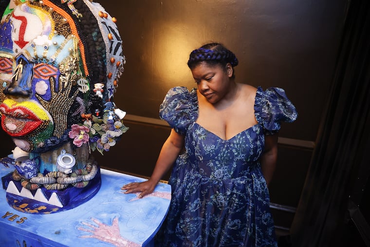 At the Colored Girls Museum, vanessa german standing next to "The Oracle" and "The Table," two characters in the exhibit "The House, The Oracle and The Table."