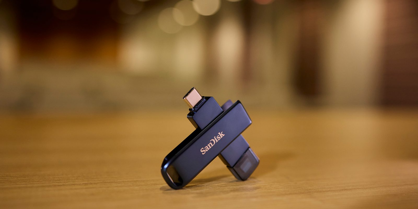 SANDISK Phone Drive for iPhone shown on a desk with out-of-focus lighting behind
