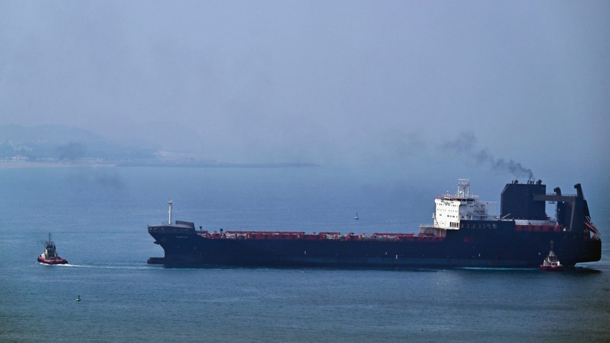TOPSHOT - A tugboat guides a ship at the Khor Fakkan Container Terminal, the only natural deep-sea port in the region and one of the major container ports in Sharjah Emirate, along the Gulf of Oman on July 14, 2026. Tehran announced it was closing the Strait of Hormuz on July 12 and launched missiles and drones at its Gulf neighbours, in retaliation for new US strikes following an attack by Iranian forces on a merchant vessel that was abandoned in flames by its crew. (Photo by AFP via Getty Images) /