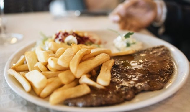 Succulent grilled ribeye steak, accompanied by French fries, salad, and aioli