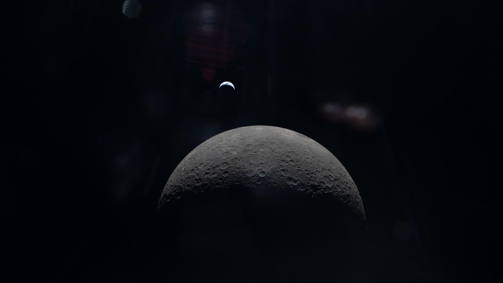 a dark grey crescent on a black background with a blue-white crescent visible in the far distance