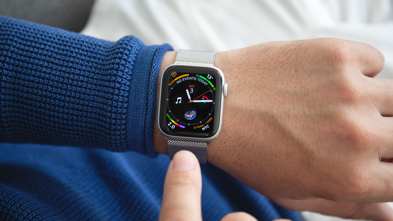 An Apple Watch Series 4 on a wrist showing an analog clock.