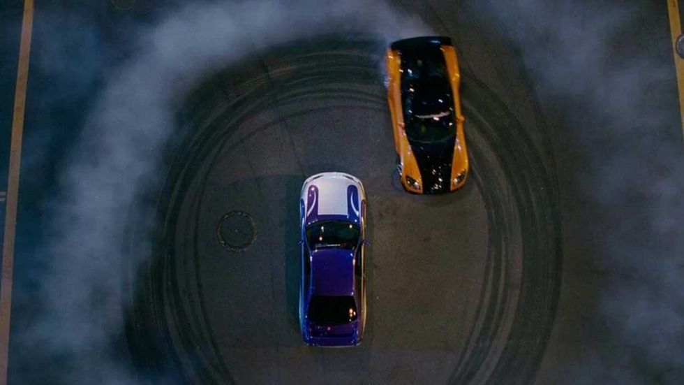 A car doing donuts around another car in The Fast and the Furious: Tokyo Drift