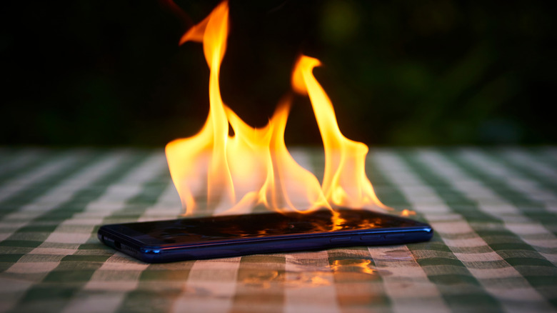 A smartphone catching fire while sitting atop a table