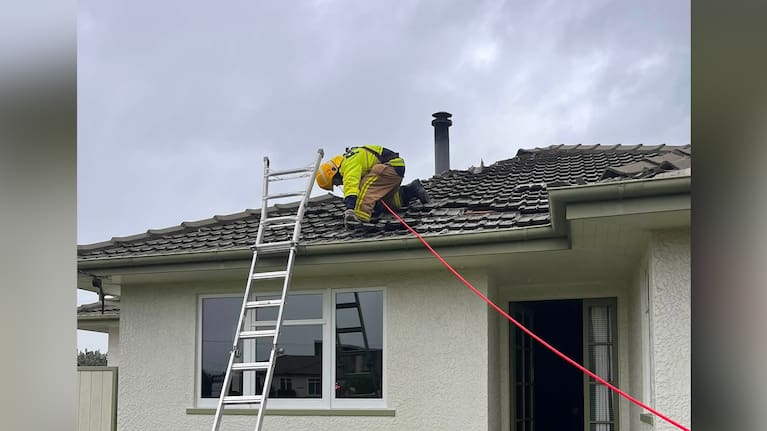 A firefighter securing a roof damaged by a miniature tornado in Richmond, south of Nelson. (Source: Richmond Volunteer Fire Brigade)