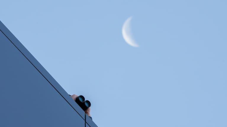 A law enforcement officer uses binoculars to watch from the roof of the Fourth District Courthouse in Provo, Utah.