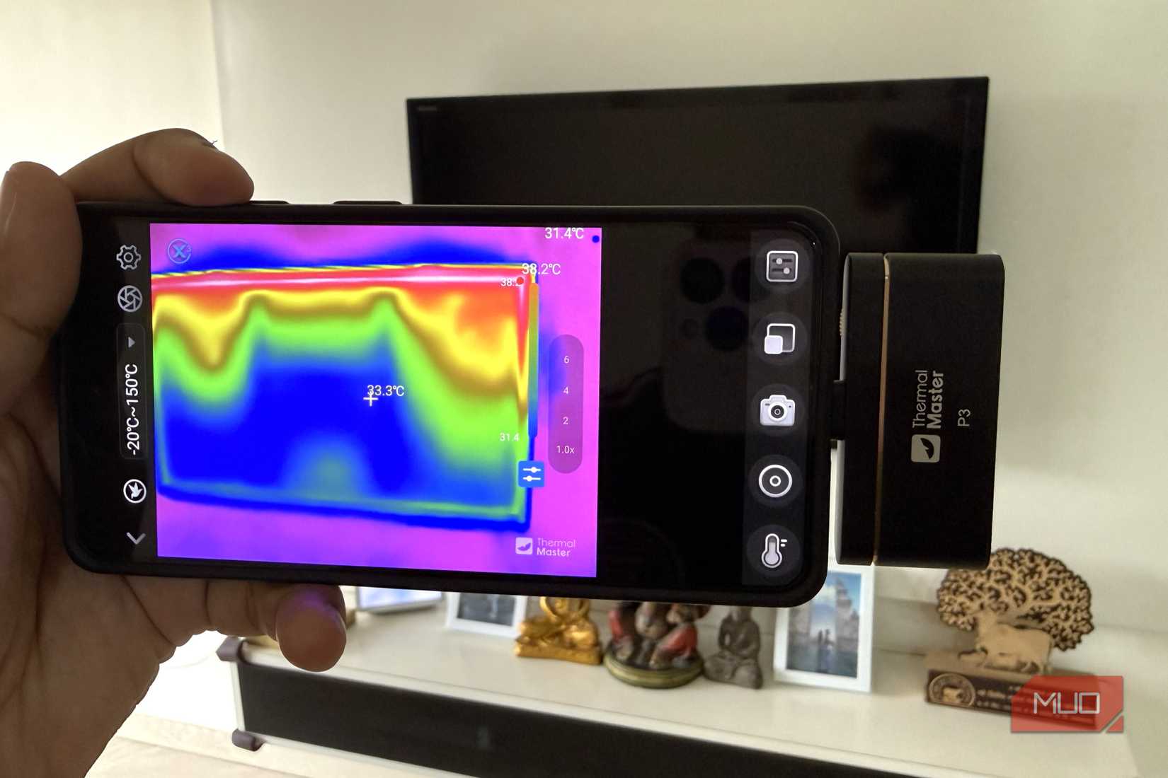 A phone connected to a thermal camera pointing at TV