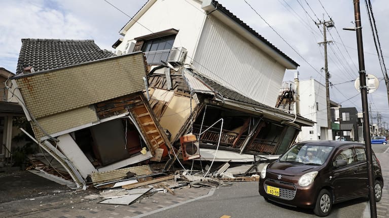A vehicle passes by collapsed houses after an earthquake in Yatsushiro, Kumamoto prefecture, Wednesday, July 29, 2026.