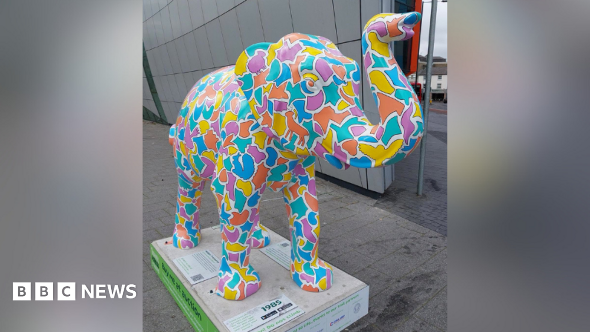 A colourful sculpture of an elephant with its trunk raised.